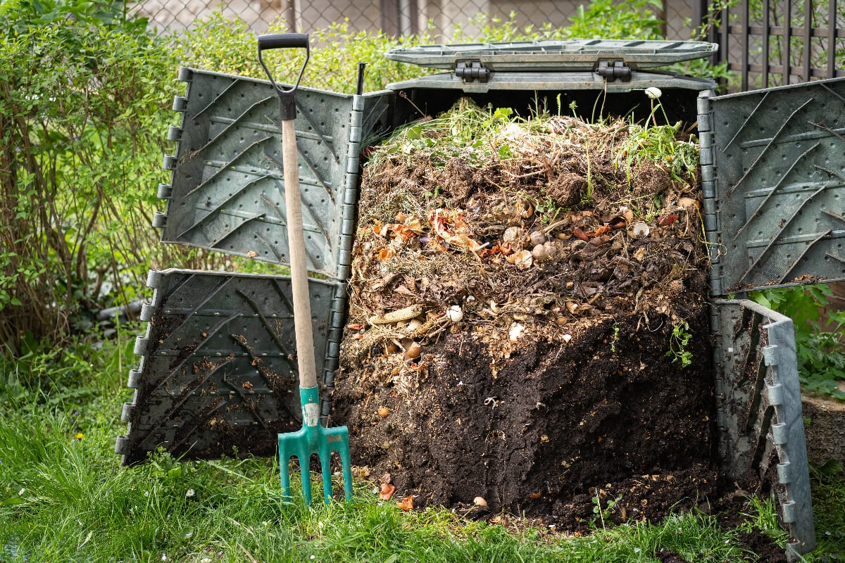 Old open fronted compost bin with layers of organic material inside.