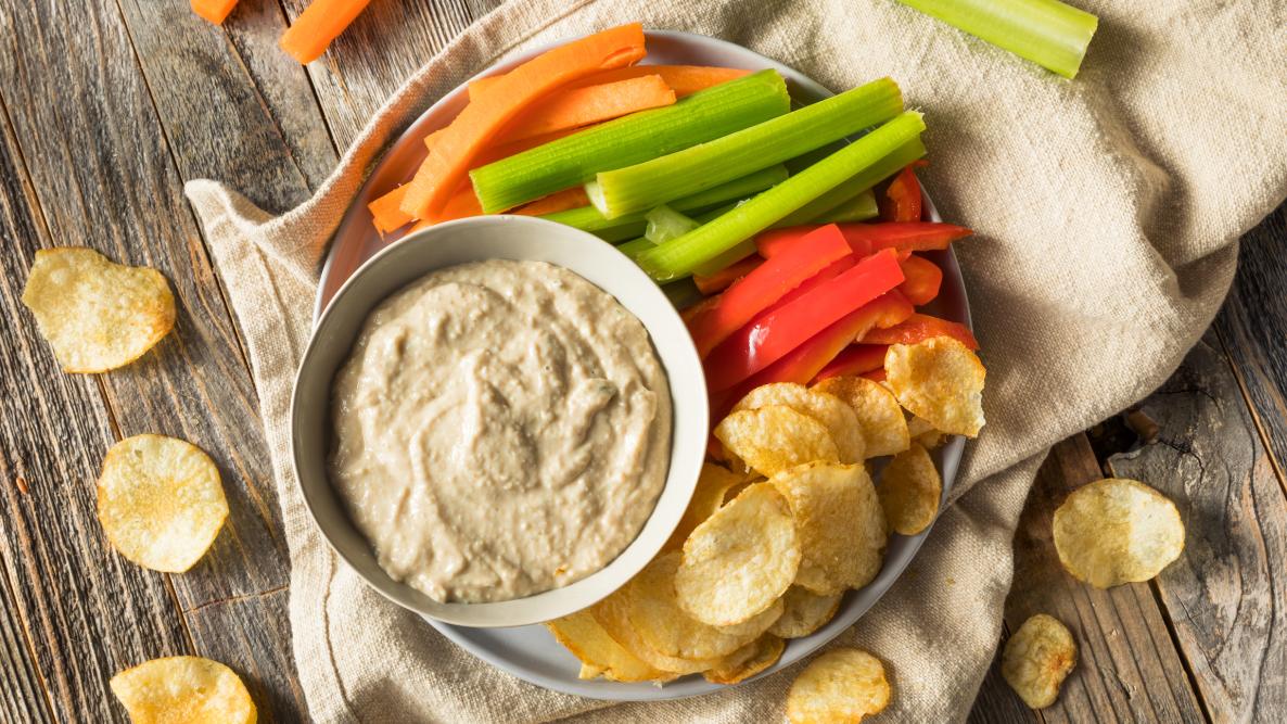 fresh onion dip with crudite and chips on a table